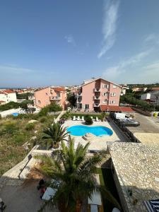 a view of a swimming pool with palm trees and buildings at Apartments Roxsi in Novalja