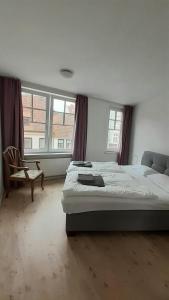 a bedroom with two beds and a chair and windows at Likedeeler Am Stadthafen in Lübeck