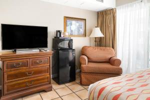 a hotel room with a television and a chair at Tidelands Caribbean Boardwalk Hotel and Suites in Ocean City