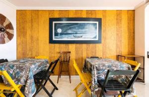 アハイアウ・ド・カボにあるMaré Alta Suítes de Temporada - Seaviewのテーブル2台と椅子、壁掛けテレビが備わる客室です。