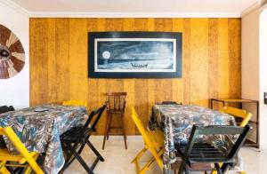 a room with two tables and chairs and a tv on the wall at Maré Alta hospedagem in Arraial do Cabo