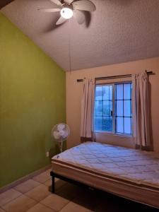 um quarto com uma cama, uma janela e uma ventoinha de tecto em Agusticidad en Cuernavaca em Emiliano Zapata