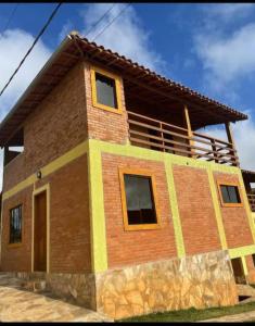 a brick house with a balcony on top of it at Casa do Eduardo ibitipoca mg in Conceição da Ibitipoca
