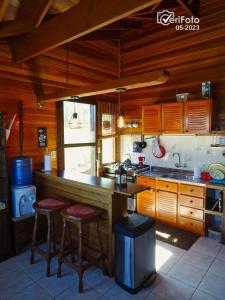 a kitchen with wooden cabinets and a counter with stools at La Serena casa de campo y senderismo in Villa Serrana
