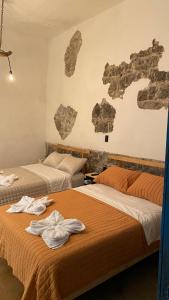 2 camas en una habitación con rocas en la pared en El Acicate Hospedaje, en Cuetzalán del Progreso