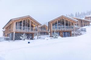 a group of wooden buildings in the snow at Bergresort Hauser Kaibling by ALPS RESORTS in Haus im Ennstal