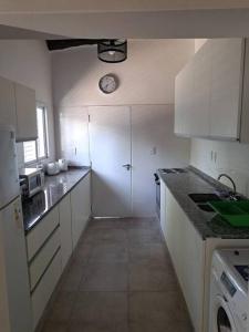 a kitchen with white cabinets and a clock on the wall at Almirante Brown 235 , Dpto 5 in San Martín