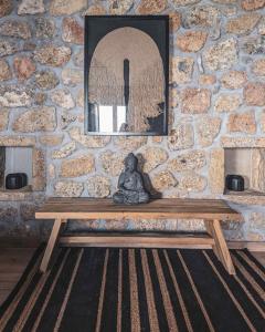 a statue sitting on a wooden bench in front of a stone wall at Three Dots Boutique Suites in Soúlion