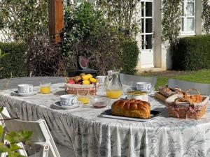 a table with bread and baskets of fruit and orange juice at Maison de Famille près de Montargis - Élégance et Confort en Forêt - FR-1-590-354 in Paucourt