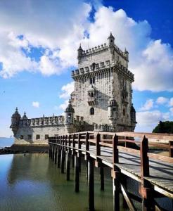 a large white tower with a bridge in the water at Lisbon South Bay Apartment with terrace in Almada