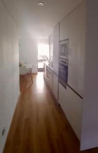 een keuken met witte muren en een houten vloer bij Lisbon South Bay Apartment with terrace in Almada