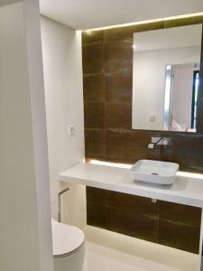 a bathroom with a sink and a toilet and a mirror at Lisbon South Bay Apartment with terrace in Almada