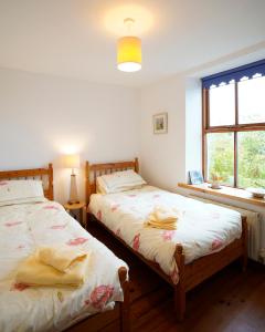 1 dormitorio con 2 camas y ventana en Meadow Cottage, en Belmullet