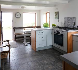 a kitchen with white cabinets and a stove top oven at Meadow Cottage in Belmullet