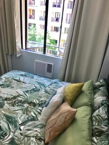 een bed met kussens in een kamer met een raam bij Manila Airport Staycation near NAIA Terminal 3 in Manilla