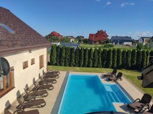 a swimming pool with lounge chairs and a house at Apartamenty przy basenie blisko morza Brown in Puck