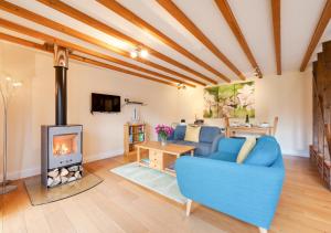 a living room with a blue couch and a fireplace at Hawkeswade Barn in Ufford