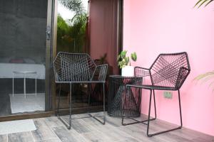 dwa krzesła i stół obok różowej ściany w obiekcie Hotel Daleese w mieście Uvita
