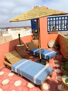 a patio with umbrellas and chairs on a roof at Riad Dar Latigeo in Essaouira