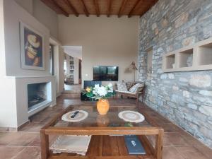 a living room with a table and a stone wall at Luxury Villa in Sklithri in Skiathos Town