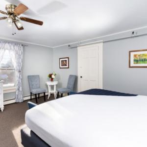 a bedroom with a bed and two chairs and a ceiling fan at The New London Inn in New London