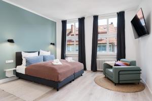 um quarto com uma cama e uma cadeira em FLATLIGHT: Hildesheim Angoulemeplatz em Hildesheim