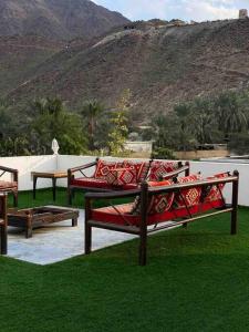 two benches sitting on the grass with a mountain in the background at ALWADI Chalet - Khorfakkan in Khor Fakkan
