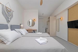 a white bedroom with two beds and a mirror at Noa Suites in Arillas