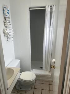 La salle de bains blanche est pourvue d'une douche et de toilettes. dans l'établissement The Admiral Hotel/Motel, à Ocean City