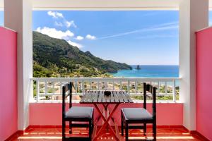 einen Tisch und Stühle auf einem Balkon mit Meerblick in der Unterkunft The Pink Palace Hostel in Agios Gordios