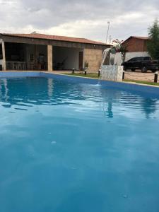 a large blue swimming pool in front of a house at Casa privado com 3 quartos e piscina in Logradouro