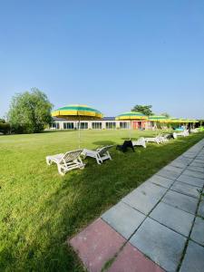 una fila di panchine in un campo con un edificio di B&B Villa degli Angeli a Bernalda