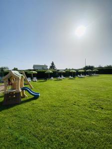 un parque infantil con un tobogán en un campo de césped en B&B Villa degli Angeli, en Bernalda