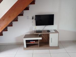 a living room with a tv and a desk with a television at Bangalô 7b Praia de Guaratiba in Prado