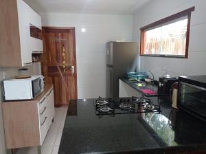 a kitchen with a stove and a microwave at Bangalô 7b Praia de Guaratiba in Prado