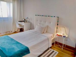 een slaapkamer met een wit bed en een tafel bij Comfortable bedrooms in apartment with river view in Almada