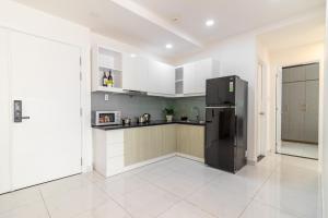 una cucina con armadietti bianchi e frigorifero nero di New Luxury 2BR Apt - Terra Royal Ho Chi Minh City ad Ho Chi Minh