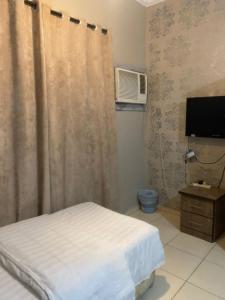 a bedroom with a bed and a tv and a curtain at قصر المنار in Jeddah
