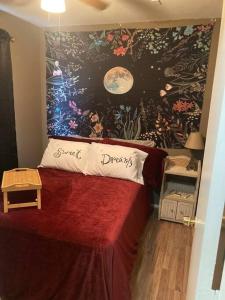 1 dormitorio con cama roja y pared de flores en Hippie Haus next to iconic BBQ restaurant, en Lakehills