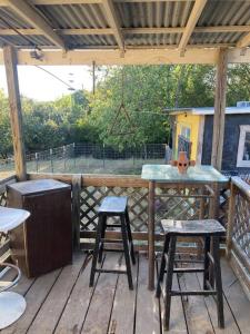 un patio con una mesa y 2 taburetes en una cubierta en Hippie Haus next to iconic BBQ restaurant, en Lakehills