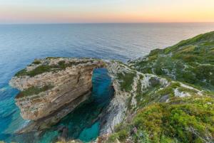 an arch in the rocks near the ocean at sunset at Dimitris Cottage in Apergátika