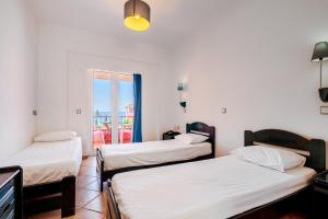 three beds in a room with a balcony at Pink Palace Beach Resort in Agios Gordios