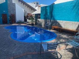 uma piscina com duas cadeiras e um banco em HOTEL AYRE By Baltra em Puerto Ayora