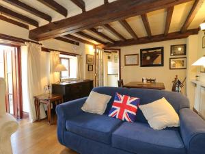 a living room with a blue couch with pillows at Granary Cottage in Oasby