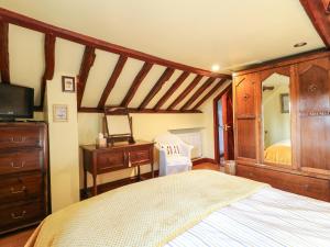 a bedroom with a bed and a dresser and a mirror at Granary Cottage in Oasby