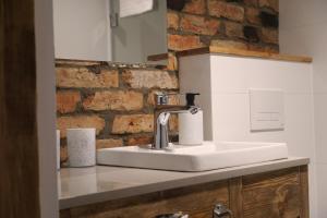 a white sink in a bathroom with a brick wall at Kamienica Na Nowo Apartamenty Warszawska in Mrągowo