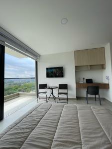ein Wohnzimmer mit einem Tisch und Stühlen sowie einem großen Fenster in der Unterkunft Apartaestudio de lujo en Cali in Cali