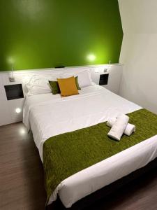 a bedroom with a large white bed with a green wall at Hôtel QUAI33 in Saint-Étienne