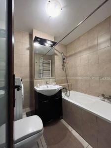 een badkamer met een wastafel, een bad en een toilet bij Nairo Aparthotel in Braşov