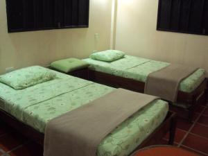three beds in a room with green blankets at El Yaque Ranch in El Yaque